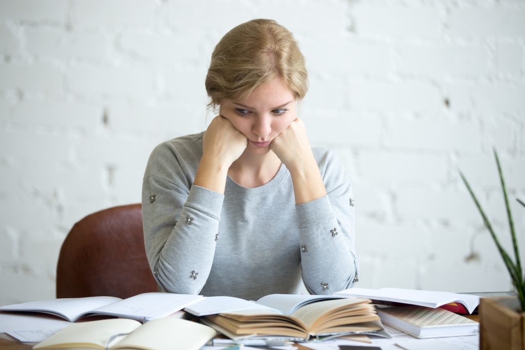 Mujer sentada en un escritorio estudiando con mala cara